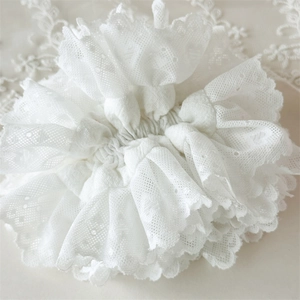 Chouchou élégant en dentelle blanche avec plis superposés et motifs de broderie florale