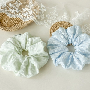 Detailansicht von pastellgrünen und blauen Blumen-Scrunchies mit Spitzenakzent