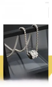 Detailed macro view of silver titanium steel cylinder pendant with shiny crystals on box chain