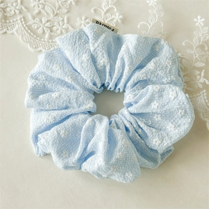 Detail eines hellblauen Blumen-Scrunchies mit Seersucker-Struktur und feinem weißen Muster