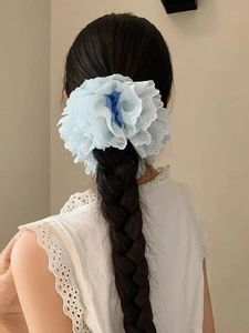 Détail d'un chouchou géant en dentelle bleu clair sur une queue de cheval tressée
