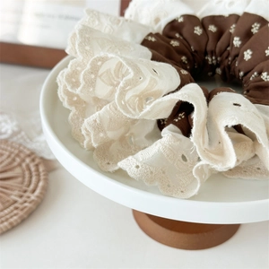 Detail of embroidered lace hair scrunchie with floral pattern and vintage layered design