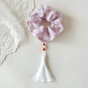 Detail view of floral scrunchie with long white tassels and red bead accents