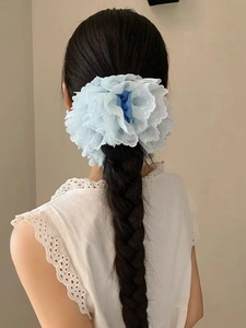 Détail d'un chouchou en dentelle bleu clair avec fleur en maille multicouche sur queue de cheval