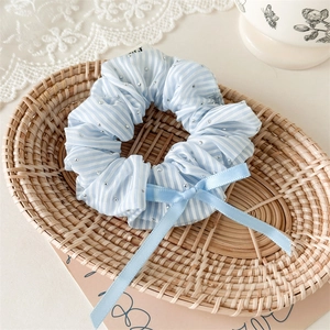 Detailed view of light blue striped scrunchie with rhinestones and ribbon bow accessory