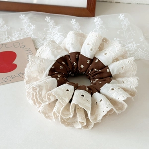 Macro shot of coffee and beige pleated hair scrunchie with floral lace and embroidery