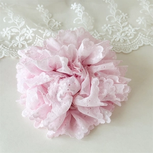 Détail d'un chouchou en dentelle rose clair avec tissu multicouche et bords festonnés