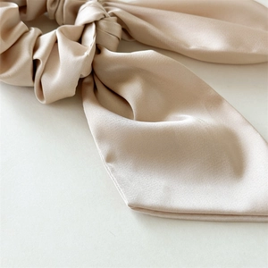 Dettaglio di un elegante elastico per capelli in raso champagne con fiocco setoso