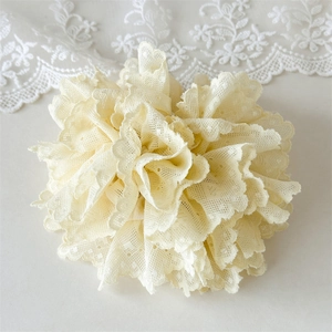 Gros plan sur un chouchou en dentelle ivoire avec broderies et plis effet fleuri
