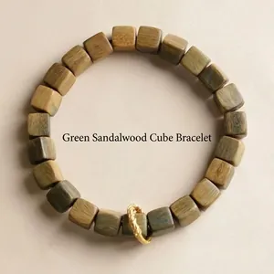 Bracelet en bois de santal naturel avec anneau doré texturé sur fond minimaliste chic