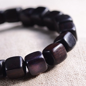 Bracelet en bois d'ébène naturel avec perles carrées sur fond de lin rustique chic