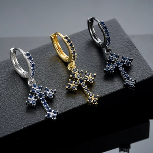 Detail van kruis oorringen in zilver, goud en zwart met ingelegde blauwe zirkonia