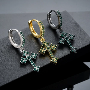 Gedetailleerd zicht op de kruis oorbellen in zilver, goud en zwart met groene zirkoon