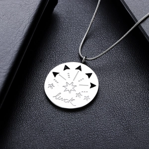 Pendentif étoile argenté avec gravure Luck sur une surface en cuir noir