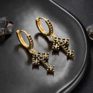 Macro-opname van gouden kruis oorbellen met zwarte zirkonia in een gothische sieradenstijl