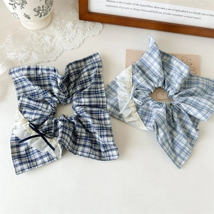 Close-up of blue plaid scrunchies with white lace edges and delicate ribbon bows