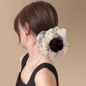 Détail d'un chouchou en tulle crème avec rubans lilas pour coiffure style ballet
