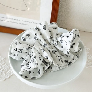 Détail de la texture d'un chouchou floral blanc avec imprimé noir sur un plateau