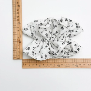 Chouchou large en coton blanc à fleurs mesurant 14cm de large sur une échelle