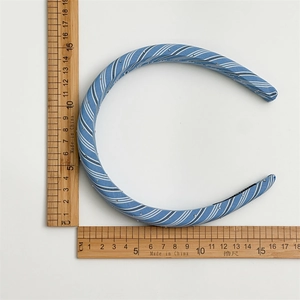 Blue plaid fabric sponge headband with small rhinestones shown on a scale measuring grid