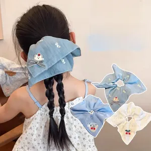 Détail de la broderie ours bleu denim et du foulard à cheveux tricoté à motif cerise