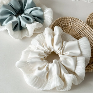 Dettaglio macro di elastici scrunchie giganti in raso con volant in avorio e blu