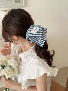 Detail of blue striped bow scrunchie with hand made label on a low ponytail