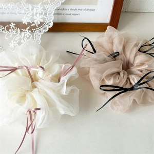 Détail de chouchous en organza avec rubans de satin blanc et abricot pour un style élégant