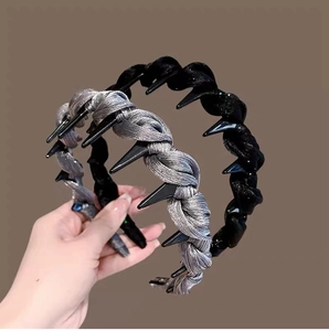 Detail showing hand holding black and silver twisted headbands with metallic accents