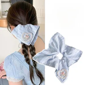 Détail du chouchou à carreaux bleu clair avec dentelle en cœur et perle rose élégante
