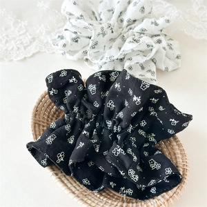 Détail de chouchous en coton à fleurs noir et blanc dans un panier en osier rustique