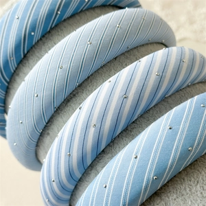 Close-up of blue and white striped padded headband with silver metallic accents