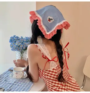Detail of blue kerchief with cherry embroidery and matching red gingham dress