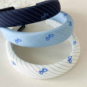 Detail of three thick padded cloth headbands with blue striped patterns and bow prints