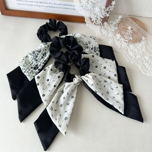 Close-up of three floral print scrunchies with long ribbons in black and white chiffon