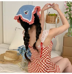 Detail of blue denim style headscarf with red cherry embroidery and floral dress