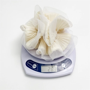 French style ivory organza ruffle hair scrunchie shown on a scale weighing 28.3 grams