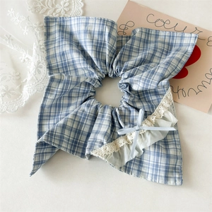 Close-up of blue plaid scrunchie with delicate white lace edges and a small ribbon bow