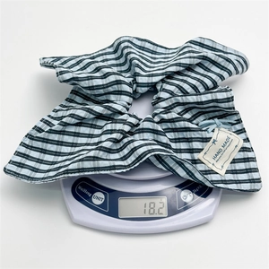 Detail view of a blue and black striped fabric scrunchie with hand made label on scale