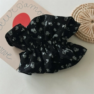 Détail de l'élastique à cheveux en coton noir à fleurs avec texture plissée