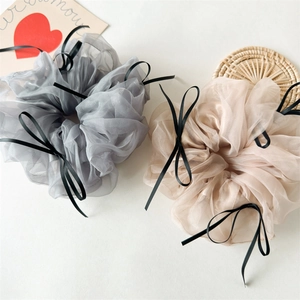 Détail de chouchous en organza translucide avec de délicats nœuds en ruban noir en lot