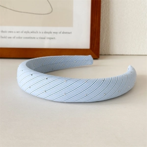 Detailed view of light blue striped fabric headband with silver studs on a clean surface