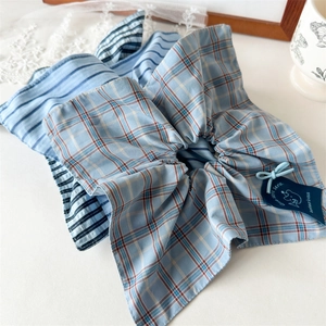Close-up of blue plaid scrunchie fabric detail with stitching and decorative tag