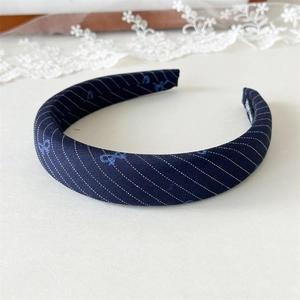 Close-up of blue fabric headband featuring white diagonal stripes and bow patterns