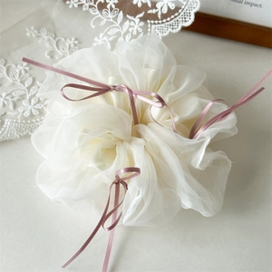 Détail d'un chouchou en organza blanc avec rubans roses et nœuds élégants