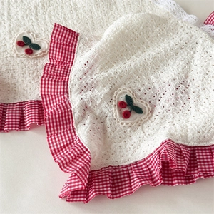 Detail of cream eyelet cotton bonnet with red gingham trim and cherry embroidery