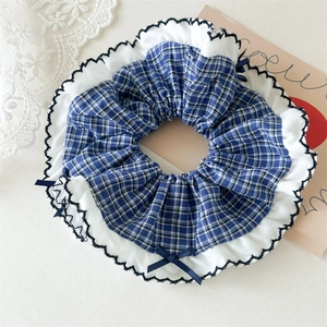 Detail of blue plaid scrunchie with white scalloped lace edges and dark blue bows