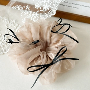 Détail du chouchou en organza champagne avec nœuds noirs pour coiffures de style ballet