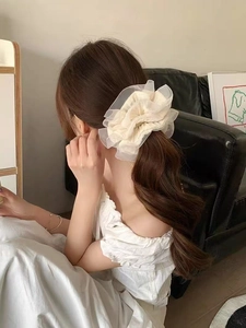Detail of elegant beige organza oversized scrunchie worn on a ponytail in soft light