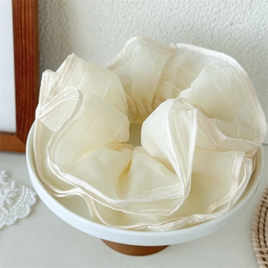 Elegant multi-layer cream mesh scrunchie displayed in a white ceramic bowl